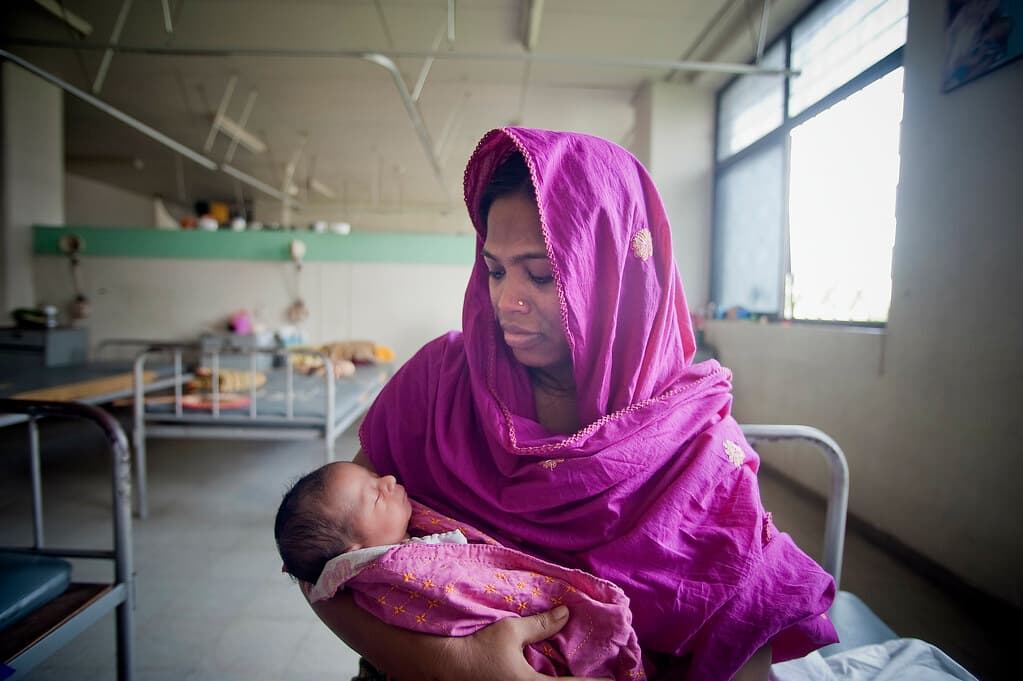 A mother holding her newborn in a hospital ward